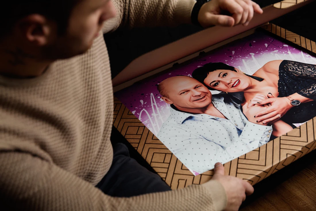 A man looks at a couple&rsquo;s portrait in an open box.